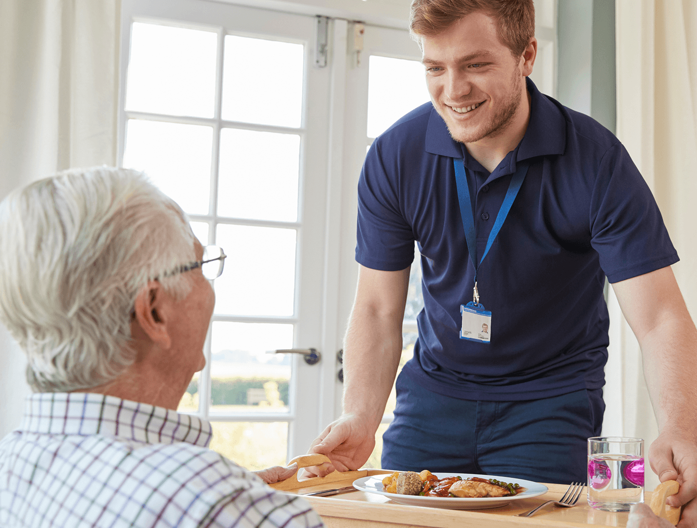 Care worker serving a meal to a client at home