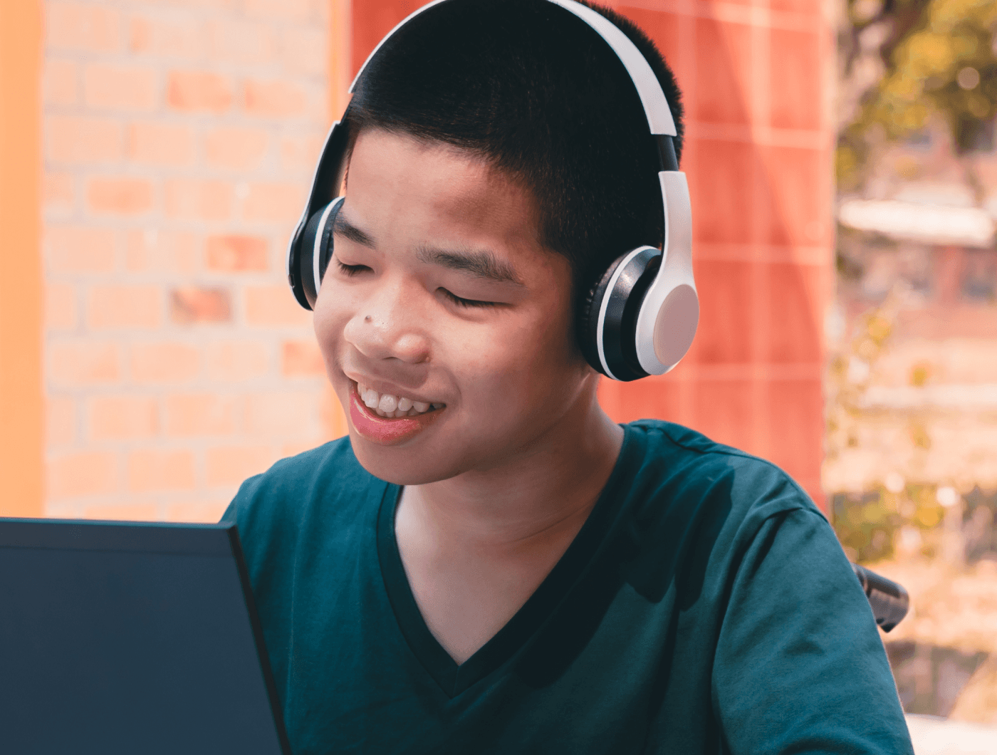 Smiling person wearing headphones while using a laptop